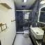 Remodeled bathroom with glass shower enclosure and modern finishes by On Demand Renovations